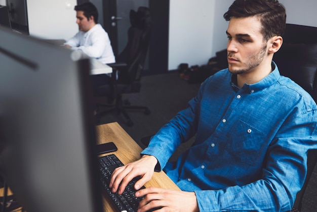 Người đàn ông trẻ tuổi sử dụng máy tính xách tay tại văn phòng