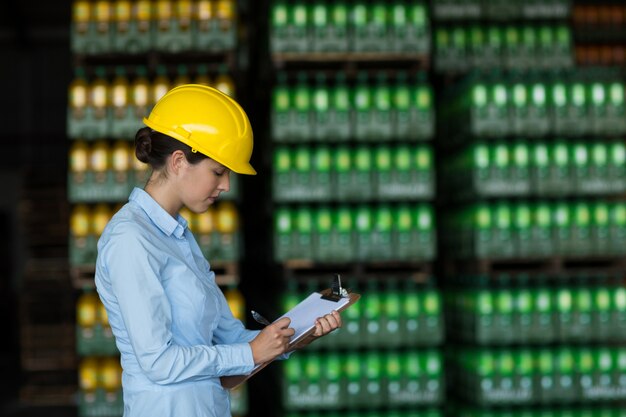 Nữ công nhân nhà máy viết trên bảng kẹp giấy trong nhà máy