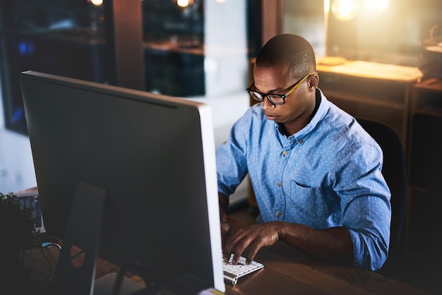 Office computer and business black man for research website programming and reading news at night Startup developer and worker online for software update networking and working on web design