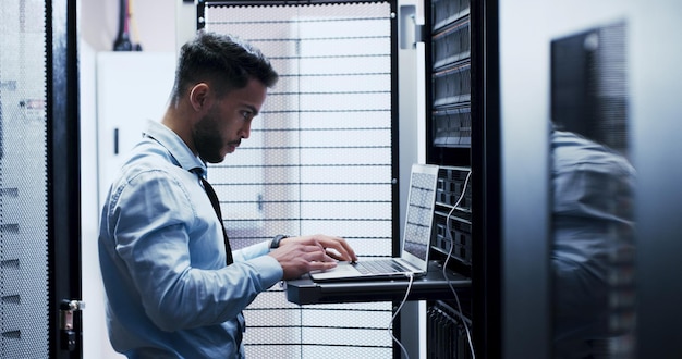 Online cybersecurity and man with laptop coding and check server performance and network engineer Data center IT specialist and person with tech for software update power cables and electricity