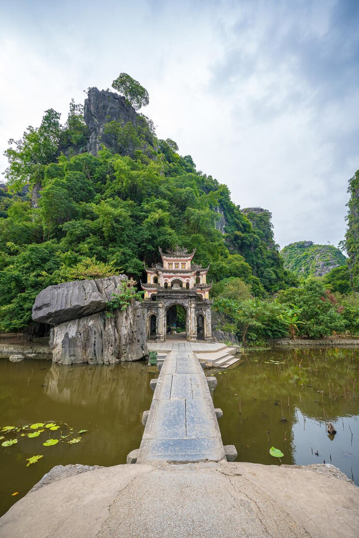 Photo outdoor park landscape with lake and stone bridge gate entrance to ancient bich dong pagoda complex ninh binh vietnam travel destination