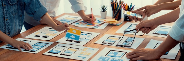 Panorama shot of frontend developer team brainstorming UI and UX designs for mobile app on paper wireframe interface User interface development team planning for userfriendly UI design Scrutinize