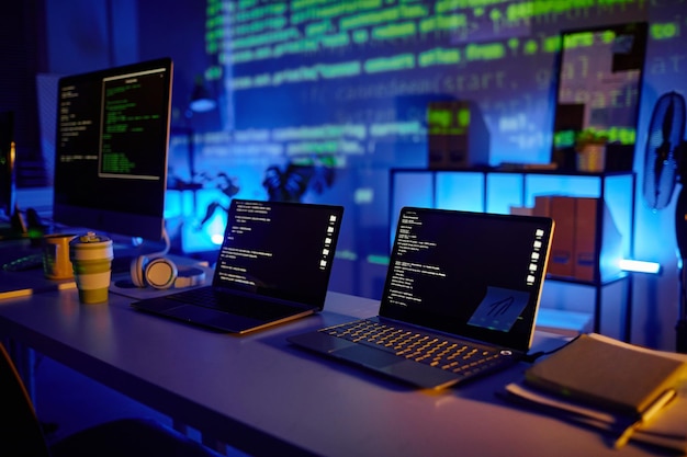 Part of large contemporary openspace bureau of diversity programmers with row of laptops and computer monitors on desks