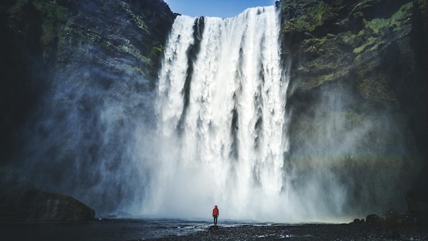person standing against beautiful waterfall