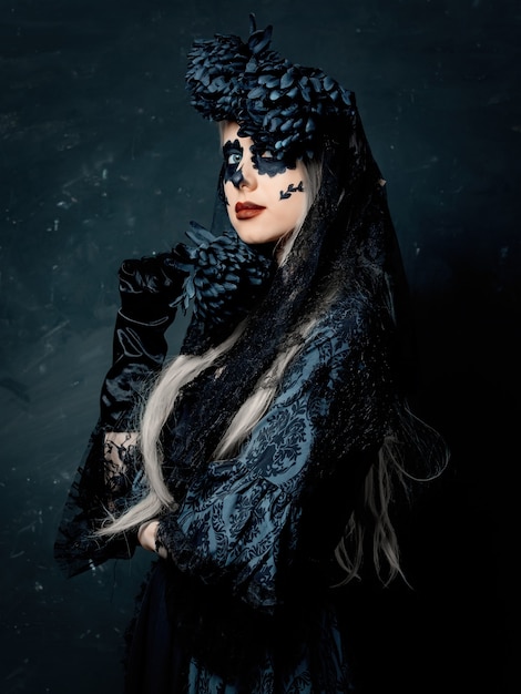 portrait of a girl in a witch costume with black flowers on a dark background. halloween holiday
