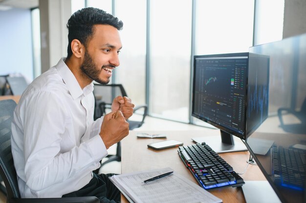 Portrait of a positive successful Indian or Arabian trader stock market broker Crypto charts on laptop screen