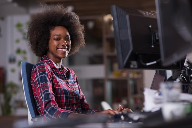 portrait of a young successful African American beautiful woman who enjoys spending a quality and joyful time while working in a large modern office