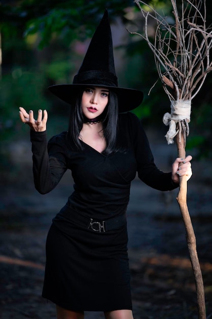 portrait of beautiful asian sexy woman wear black witch costume with broomhalloween festival concept