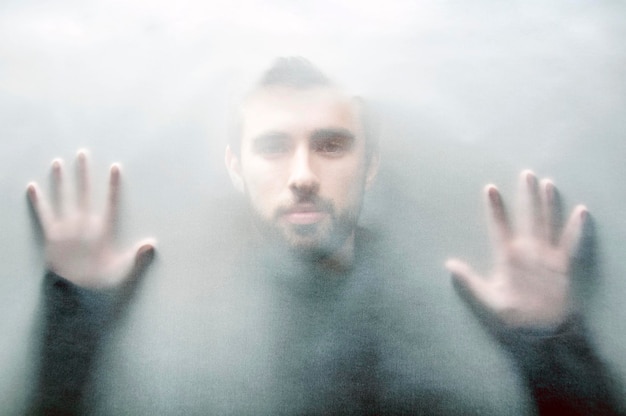 portrait of man looking through condensed glass