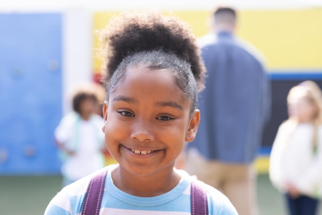 Portrait of smiling african american elementary schoolgirl in school playground, copy space