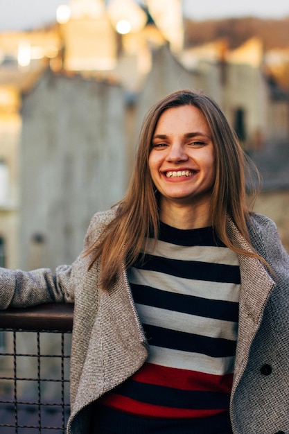 portrait of smiling young woman looking away while standing by railing