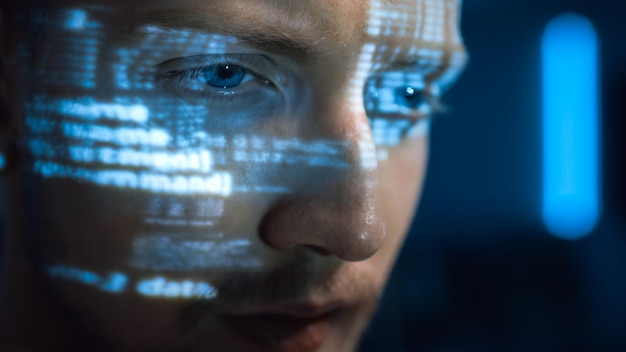 Portrait of Software Developer Hacker Working on Personal Computer Projected Code Numbers and Characters Reflect on His Face Dark Room Full of Electronics Hacking and Programming Concept