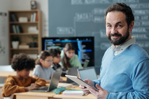 Portrait of teacher holding tablet in school classroom