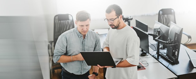 Portrait of two professional male programmers working on computer in diverse offices Modern IT technologies development of artificial intelligence programs applications and video games concept