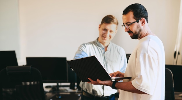 Portrait of two professional male programmers working on computer in diverse offices Modern IT technologies development of artificial intelligence programs applications and video games concept