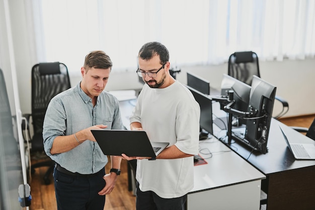Portrait of two professional male programmers working on computer in diverse offices Modern IT technologies development of artificial intelligence programs applications and video games concept