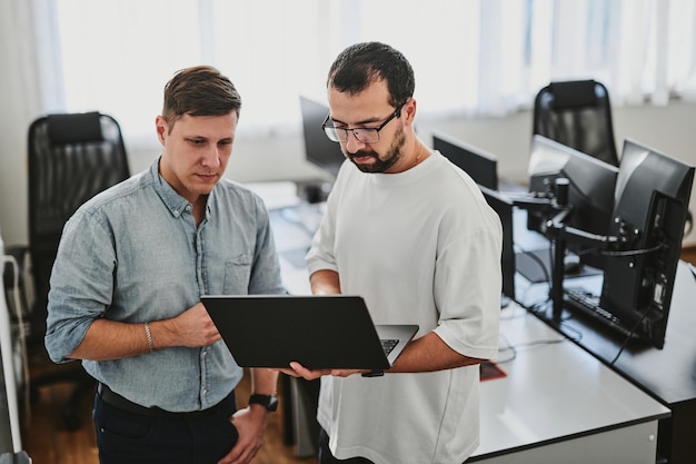 Portrait of two professional male programmers working on computer in diverse offices Modern IT technologies development of artificial intelligence programs applications and video games concept