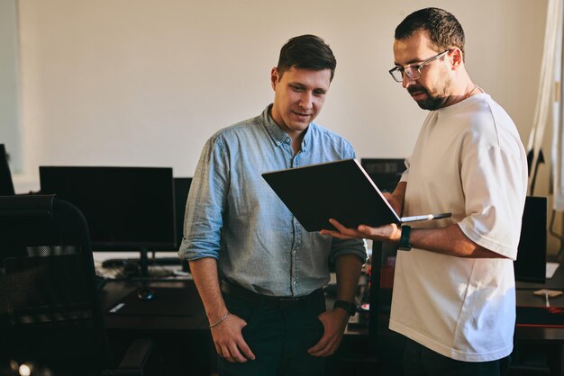 Portrait of two professional male programmers working on computer in diverse offices Modern IT technologies development of artificial intelligence programs applications and video games concept