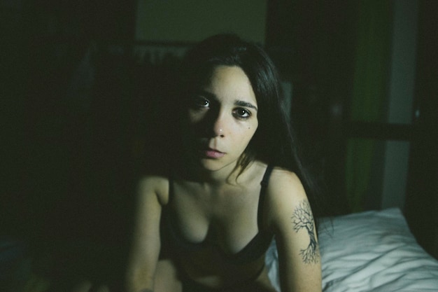 portrait of woman in bikini sitting on bed at home
