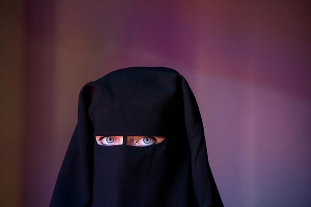 portrait of woman wearing burka against wall