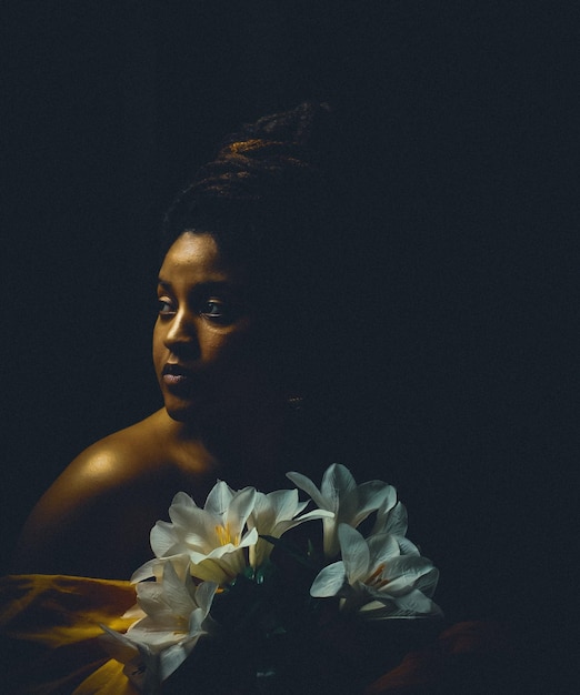 portrait of woman with white flowers against black background