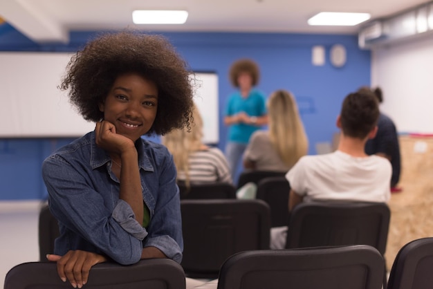 portrait of young african american business woman at modern startup office interior, team in meeting in background
