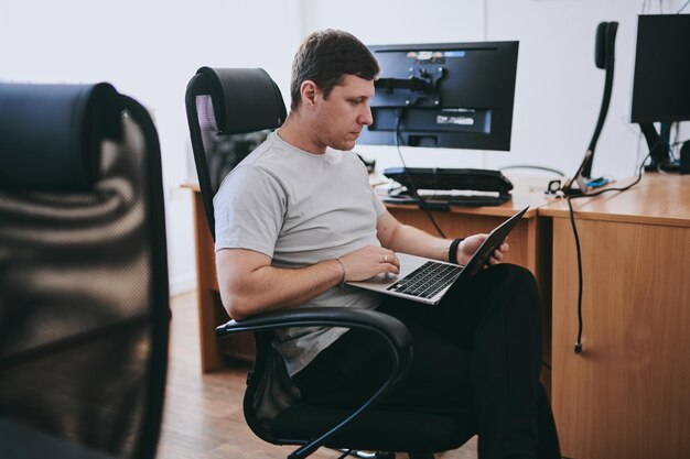 portrait of young caucasian male programmer working with laptop in office software developer it technology