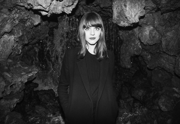 portrait of young woman standing against rock at night