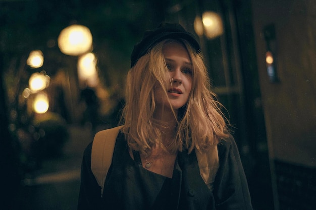 portrait of young woman with blond hair standing outdoors at night
