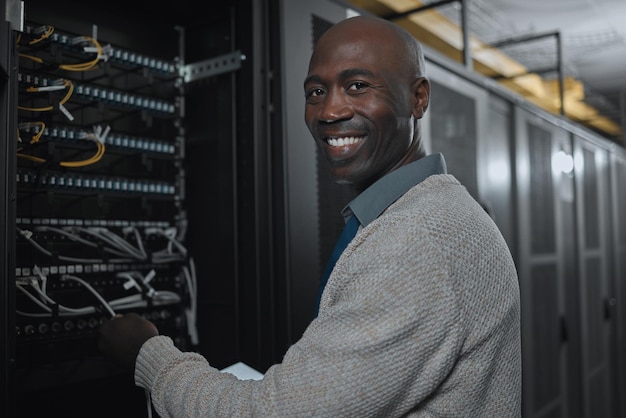 Portrait server room and black man on tablet for database maintenance or software update at night Cybersecurity face or it male engineer coder on tech for programming or networking in data center