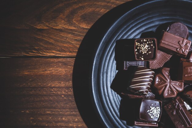 pralines on plate  on wooden base, deep shadows, close up. sweet and chocolate .
