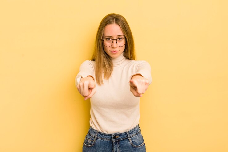 Photo pretty caucasian woman pointing forward at camera with both fingers and angry expression telling you to do your duty