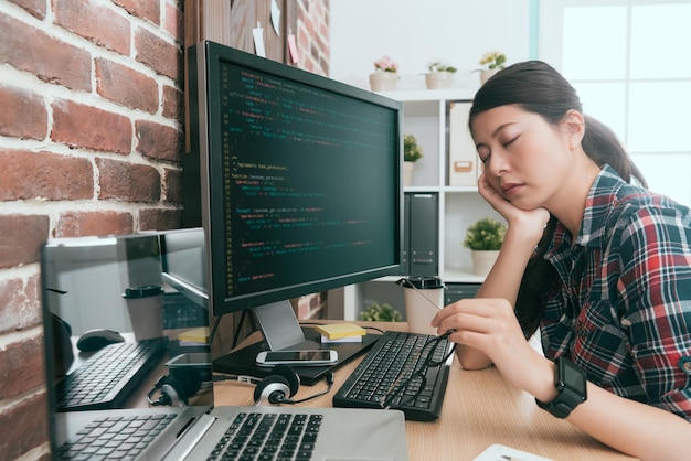 pretty elegant lady computer developer sitting in front of working computer design coding long time and feeling tired napping on desk.