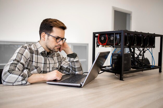Programmer setting up a mining rig for cryptocurrency mining and checking bitcoin earnings data