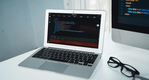 Programming code on laptop monitor and beside screen pc desktop showing website development coder Application information technology in software system Theme of workspace at home Tastemaker