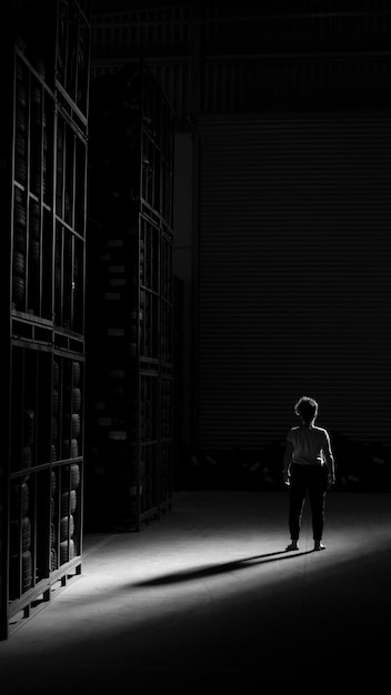 rear view of woman standing by shelves at night