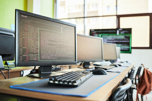Row of computer monitors displaying programming code in modern classroom