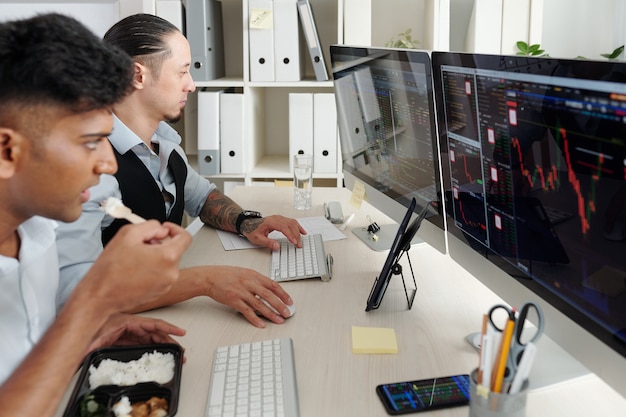 Serious traders working at office desk, analyzing stock market trends, buying and selling stocks and futures