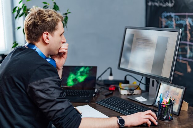 serious young man concentrated on problem on the pc screen. smart programmer is working hard in it company indoors.