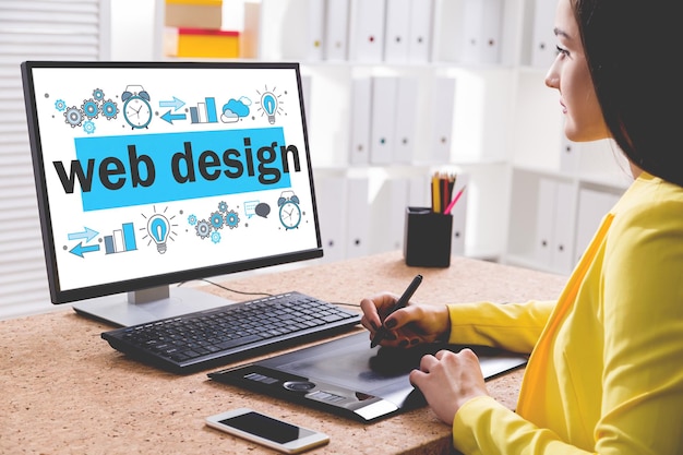 side view of a young woman in a yellow shirt drawing a stylish web design sketch on her desktop computer. concept of creative work and modern technology