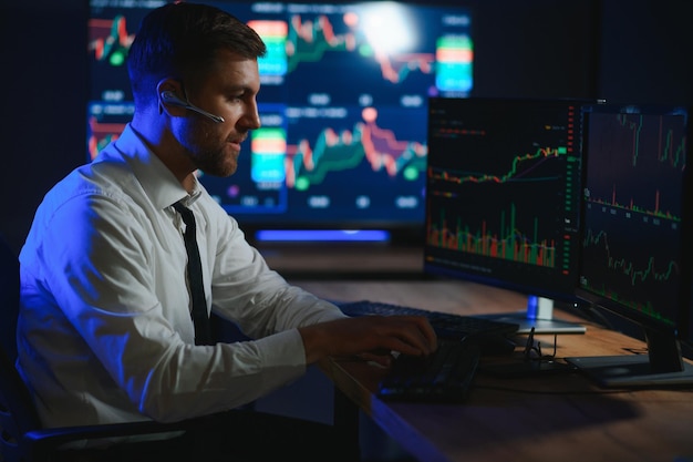 Side view of crypto broker sitting at office table analyzing market looking at screen
