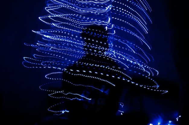 Silhouette man in illuminated christmas lights at night