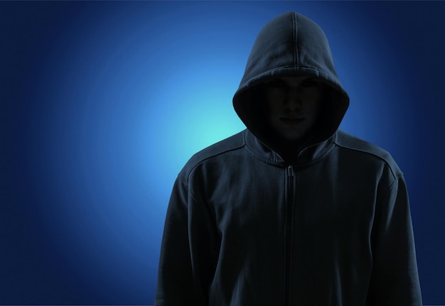 silhouette of man in the hood or hooligan over dark concrete background with copy space