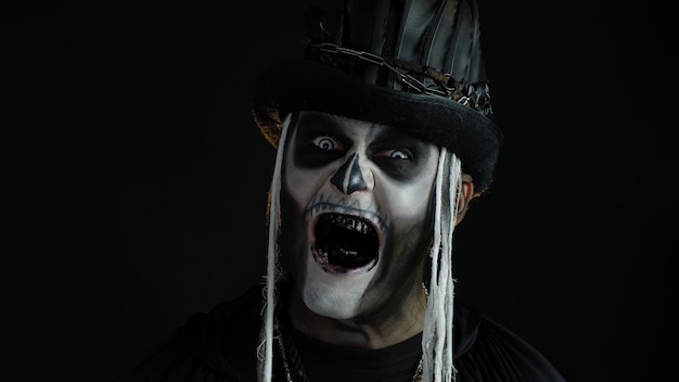 sinister man with halloween skeleton makeup turning his head and looking at camera trying to scare