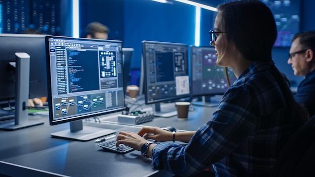 Smart Female IT Programer Working on Desktop Computer in Data Center System Control Room Team of Young Professionals Doing Code Programming