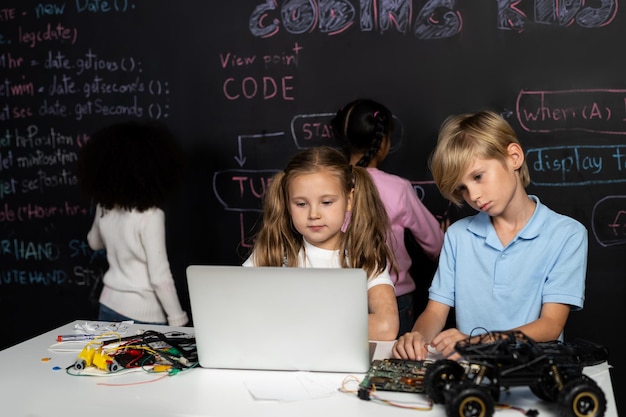 Smart girl in white bib learning robotics technology using laptop erudition