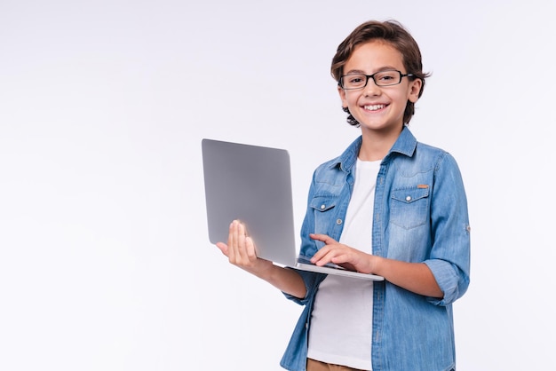Smart little boy with laptop in casual clothes isolated over white background