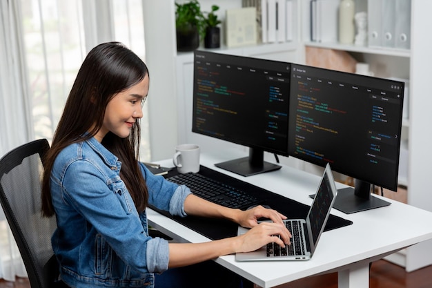 Smiling Asian IT typing online software development on laptop Stratagem