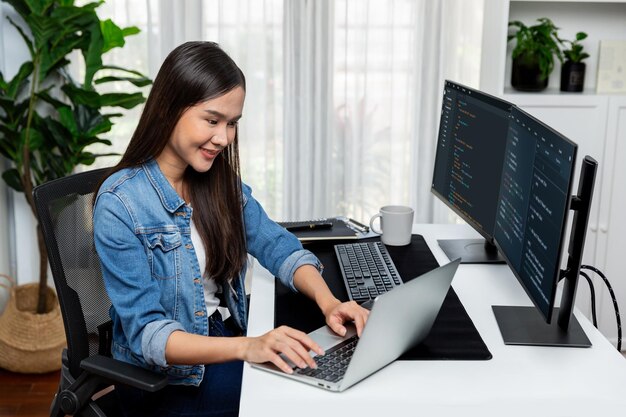 Smiling asian it typing online software development on laptop stratagem