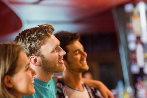 smiling brown hair standing with arm around his friends